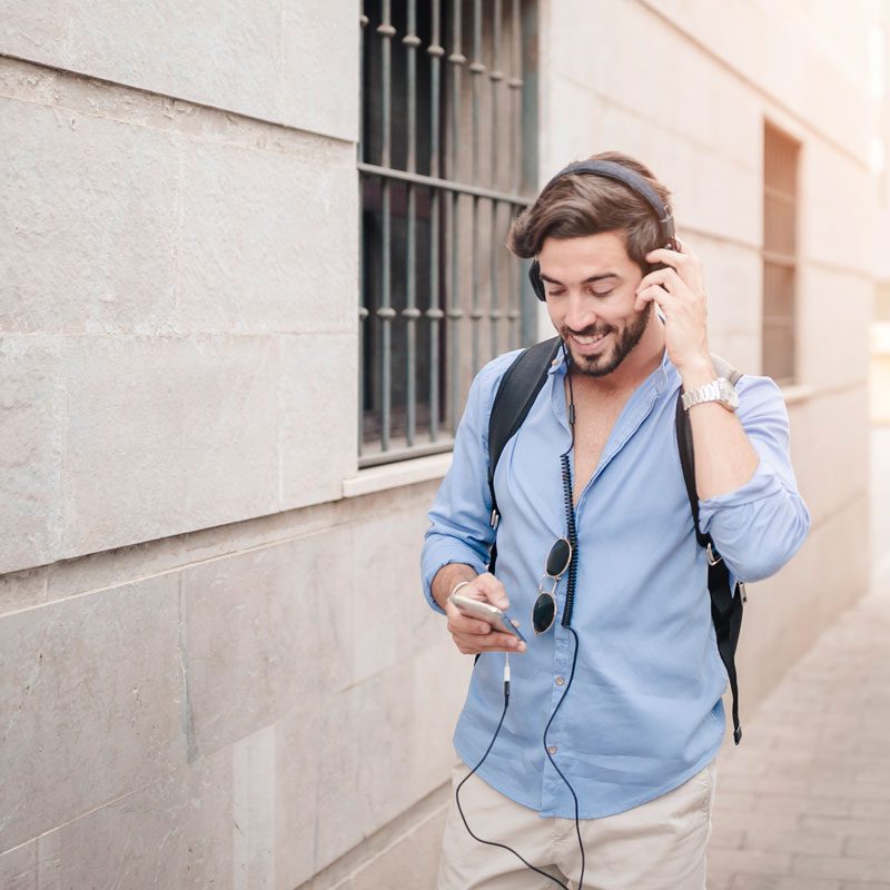 happy man walking pavement listening music